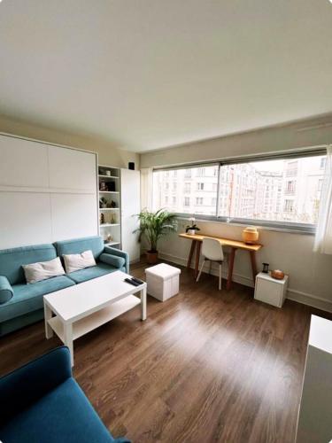 un salon avec un canapé bleu et une table dans l'établissement Cosy studio Paris 15, à Paris