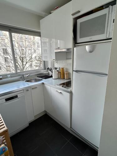 une cuisine blanche avec un réfrigérateur et un micro-ondes dans l'établissement Cosy studio Paris 15, à Paris