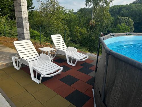 two chairs and a table next to a swimming pool at Vila Fina in Laktaši