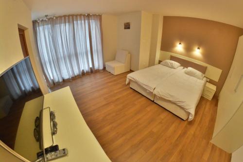 a bedroom with a white bed and a wooden floor at Villa Pirin in Simitli