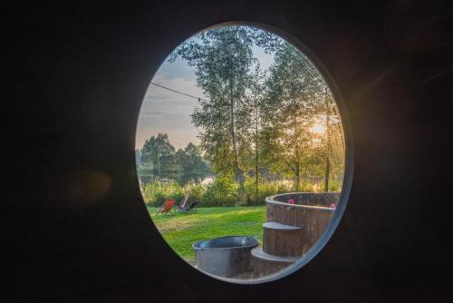 a round window with a view of a garden at Saarjärve Villa järve ääres 28-le, 8 magamistuba in Tromsi