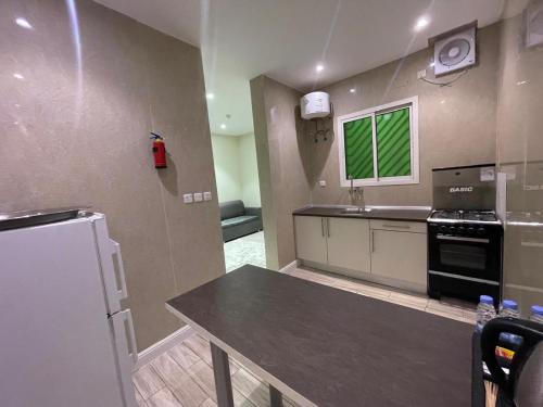a kitchen with a table and a stove and a refrigerator at N Alharbi Serviced apartments in AlUla