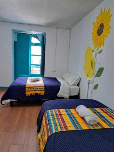 a room with two beds and a sunflower mural on the wall at Casa CarpeDM in Quito
