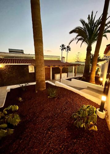 a yard with palm trees and a house with a candle at Stone Villa in Chayofa
