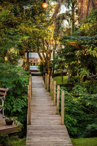 a wooden path in a park with trees and a bench at Tiny House com Banheira Privativa, Deck no Jardim com Rede Suspensa sobre o Riacho e Lareira Externa em Meio à Natureza in Imbituba