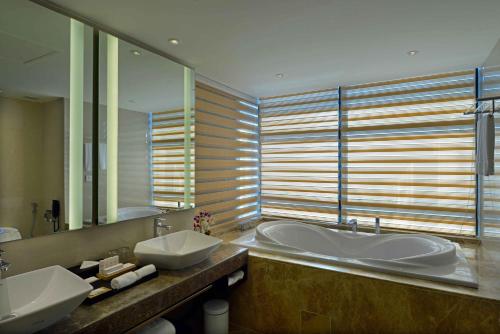a bathroom with two sinks and a tub and a mirror at Radisson Blu Chattogram Bay View in Chittagong