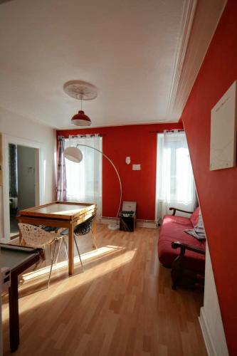 - un salon avec une table et un mur rouge dans l'établissement Appartement de caractère, à Munster