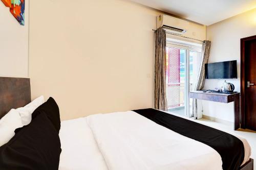 a bedroom with a white bed and a window at Super Townhouse Hebbal Bhadrappa Layout in Bengaluru