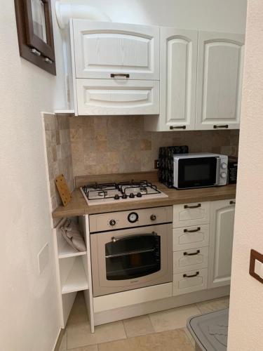 a kitchen with white cabinets and a stove top oven at Dommu Montes e Mare in Baunei