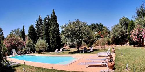 - une piscine dans un parc avec des chaises et des arbres dans l'établissement Domaine Au Coeur des Alpilles, à Maussane-les-Alpilles