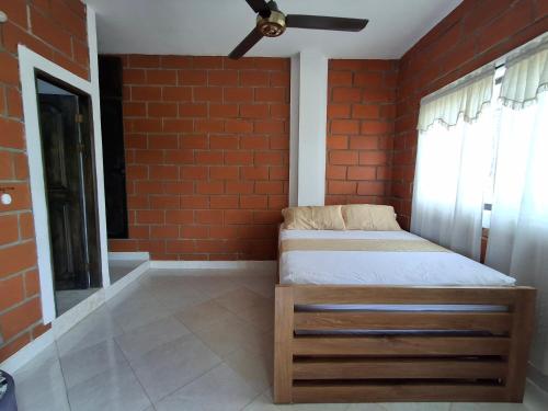 a bed in a room with a brick wall at Cabañas Mar Caribe in Necoclí