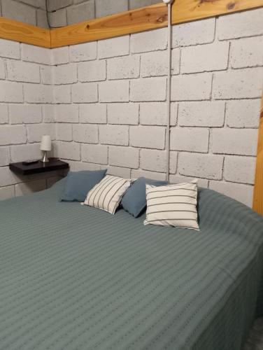 a bed with two pillows and a brick wall at Los Duraznillos in Los Antiguos