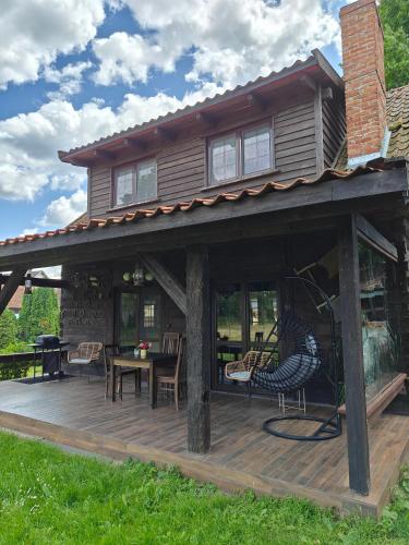a house with a deck with chairs and a table at Stay At This Magnificent 100 Year Old Barn in Ruciane-Nida