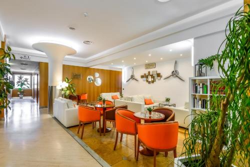 a living room with orange chairs and tables at Hotel Bologna Airport in Bologna