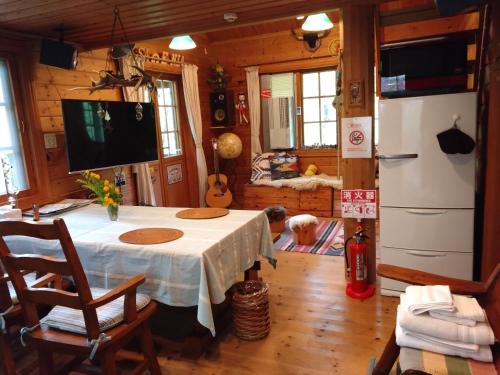a dining room with a table and a refrigerator at ぜーんぶ貸切!! 大自然の森に佇む秘密の隠れ家で心と身体を解放する... in Yuzawa