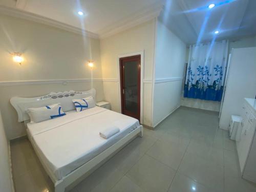 a bedroom with a white bed with blue pillows at SKY HoTEL in Brazzaville