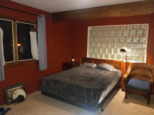 a bedroom with a bed and a chair and a window at Zoo Town House with Sauna in Missoula