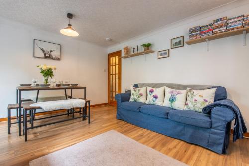 a living room with a blue couch and a table at Stylish Garden Flat Near Loch Ness in Drumnadrochit
