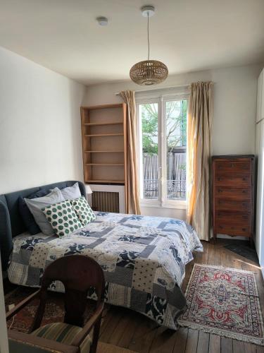 une chambre avec un lit, une chaise et une fenêtre dans l'établissement Large two-room apartment with garden, à Courbevoie