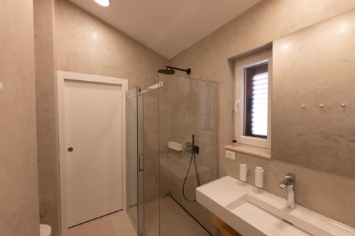 un bagno con doccia, lavandino e porta doccia in vetro di Apartment JARO a Stomorska