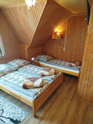 two beds in a room with wooden walls at Nad Grapą in Gliczarów