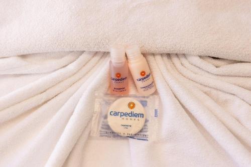 two bottles of sunscreen sitting on top of a bed at Alta Garden Housi João Pessoa by Carpediem in João Pessoa