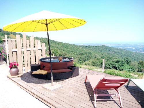 a yellow umbrella sitting on a deck with a hot tub at La Ferme Du Maquis in Antisanti