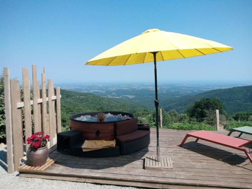 a hot tub and an umbrella on a wooden deck at La Ferme Du Maquis in Antisanti