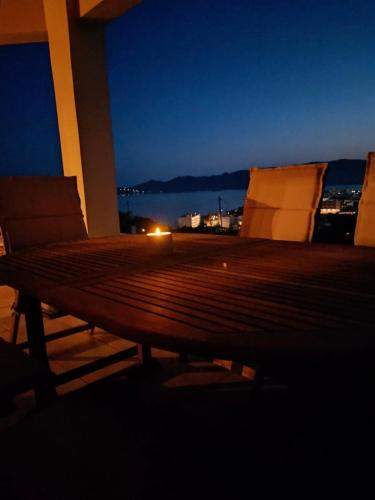 a wooden bench sitting on a balcony at night at Ethirenia in Karistos