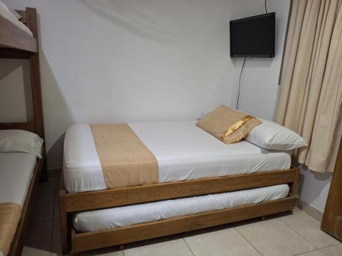 a small bedroom with two beds and a television at Hotel Cabañas Mar Caribe in Necoclí