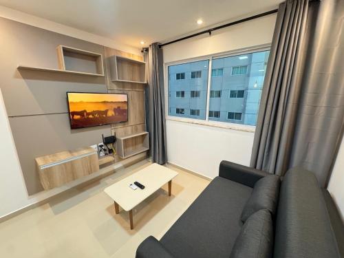 a living room with a couch and a large window at Ap próx ao Shopping com garagem, piscina e ar in Sobral