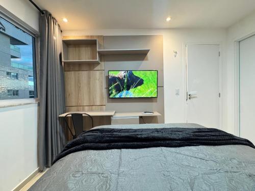 a bedroom with a bed and a tv on a wall at Ap próx ao Shopping com garagem, piscina e ar in Sobral