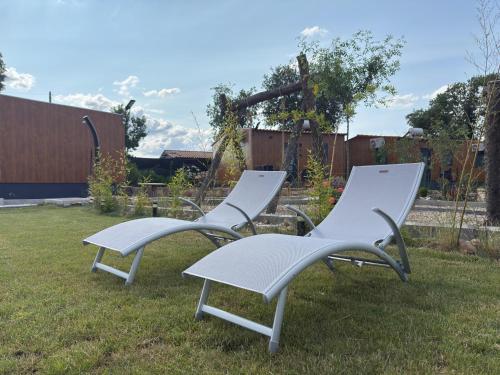 two white chairs sitting in the grass in a yard at Retiro da Vila in Sendim