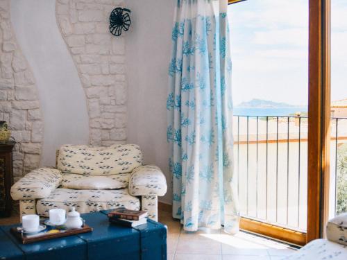 een woonkamer met een stoel en een balkon bij Apartment Crystal Sea Apartment by Interhome in Santa Maria Navarrese