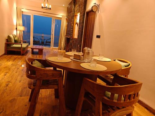 ein Holztisch mit Stühlen in einem Raum mit Fenster in der Unterkunft Iris Grove in Mukteswar