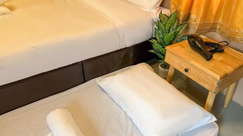 a bedroom with two beds and a table with a phone at Kampung Nature Stilt House with Paddy Field View in Balik Pulau