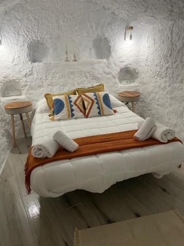 a white bed with pillows and towels on it at Cuevas Halima in Bácor