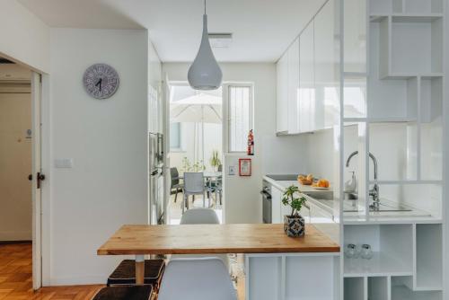 a kitchen and dining room with white cabinets and a wooden table at Cozy 1-Bedroom with Private Terrace in Palmela in Porto