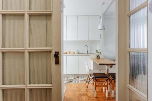 a kitchen and dining room with white cabinets and a table at Cozy 1-Bedroom with Private Terrace in Palmela in Porto