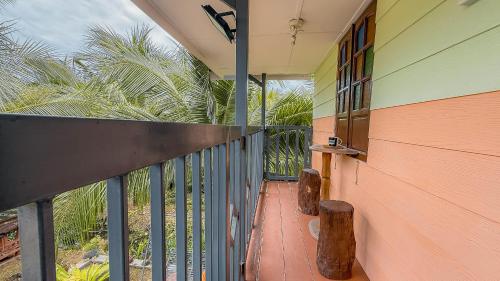 a balcony of a house with a fence and palm trees at Kampung Nature Stilt House with Paddy Field View in Balik Pulau