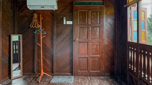 an empty room with a wooden door and a window at Kampung Nature Stilt House with Paddy Field View in Balik Pulau