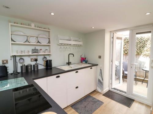 ビデフォードにあるSea Sanctuaryの白いキャビネットと黒いカウンタートップを備えたキッチン