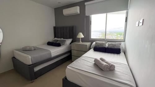two beds in a small room with a window at Magico PentHouse Duplex Frente al Mar 3 Habs FB112 in Coveñas