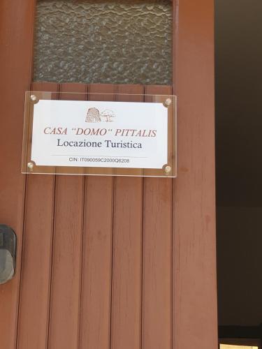 a sign on the door of a wooden fence at Domo Pittalis in Pozzomaggiore