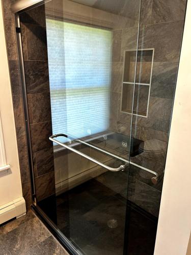 a shower with a glass door in a bathroom at House Conveniently Located by Route 1 in Falmouth
