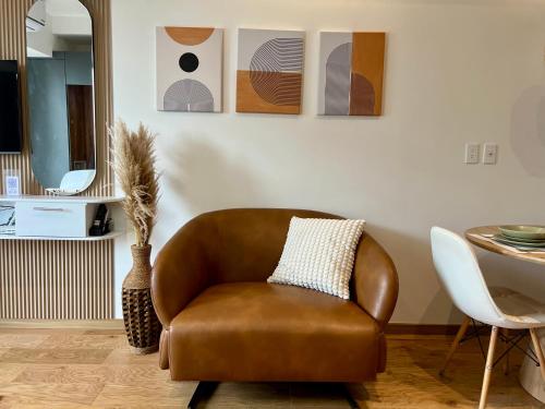 a brown chair in a living room with a table at Hermoso Loft en la Roma Norte in Mexico City