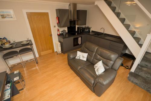 a living room with a leather couch and a kitchen at Tigh Na Cille Studio in Taynuilt