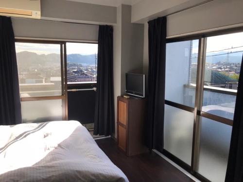 a bedroom with a bed and a tv and windows at LEGALCOURT - Vacation STAY 14717 in Akiruno