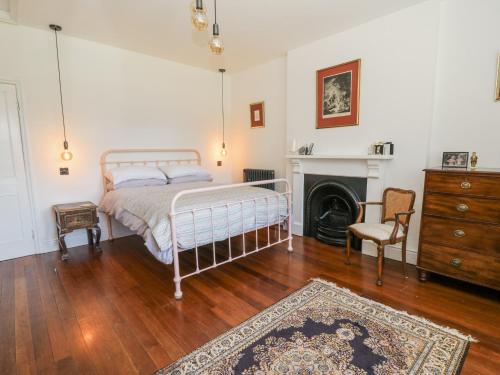 a bedroom with a bed and a chair and a fireplace at The Retreat at Glanrannell Park House in Llanwrda