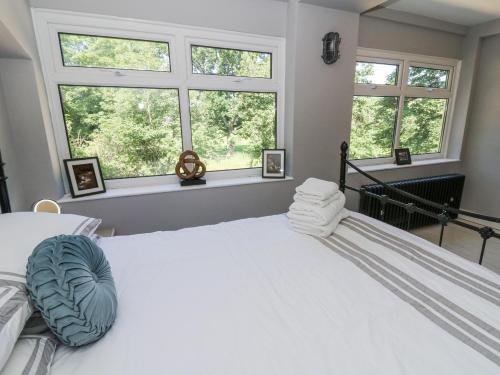 a bedroom with a white bed with two windows at The Retreat at Glanrannell Park House in Llanwrda